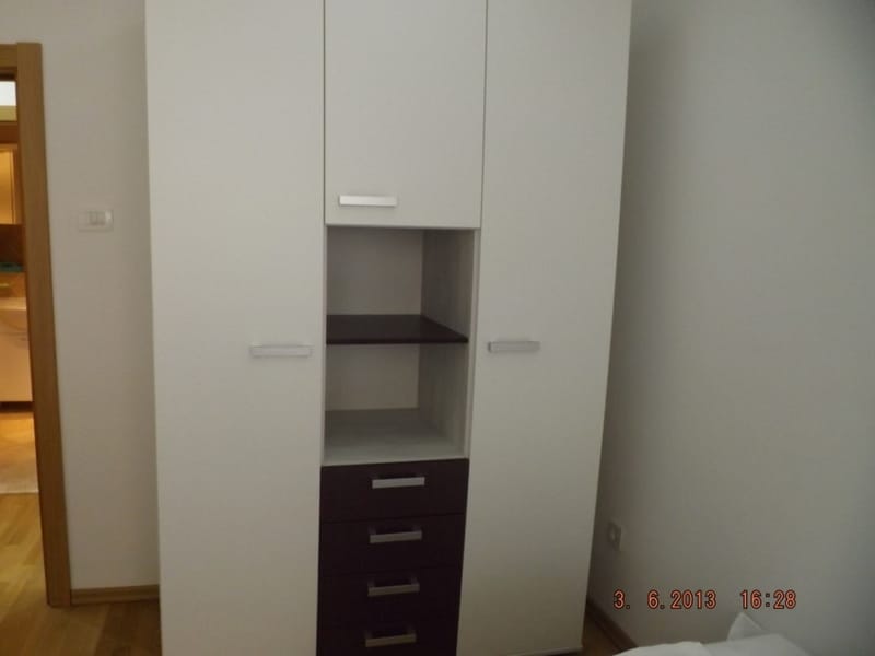 Moderan beli ormar sa tamnim fiokama u enterijeru spavaće sobe stana u Pržnu, Crna Gora.