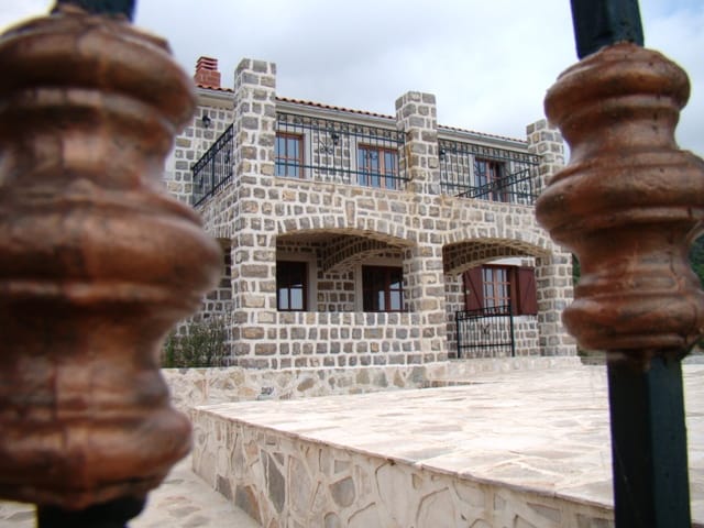 Two-story natural stone house with a terrace and wrought-iron railings in Petrovac, Montenegro.