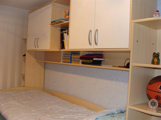 Dečja spavaća soba sa krevetom i ugrađenim svetlim ormarom u stanu u Budvi, Crna Gora.