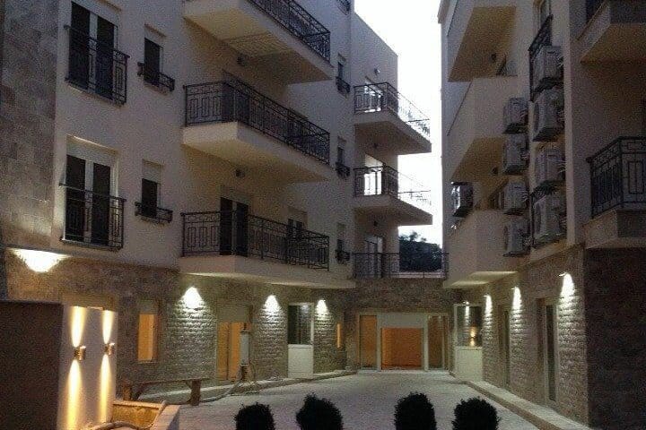 Savremeni stambeni kompleks u Pržnu, Crna Gora: fasada sa kamenim oblogama, balkonima i noćnim osvetljenjem dvorišta.