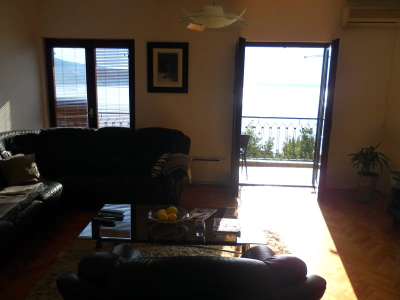 Wohnzimmer in einem Haus in Herceg Novi, Montenegro: Ledersofa, Glastisch und Zugang zum Balkon mit Panoramablick auf das Meer.
