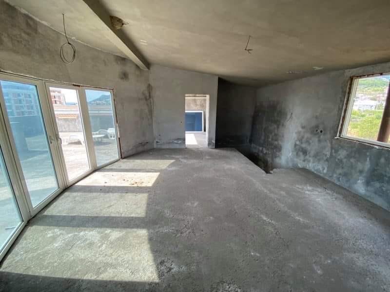 Dnevna soba u kući za završnu obradu u Šušnju, Crna Gora, sa panoramskim prozorima i izlazom na terasu.