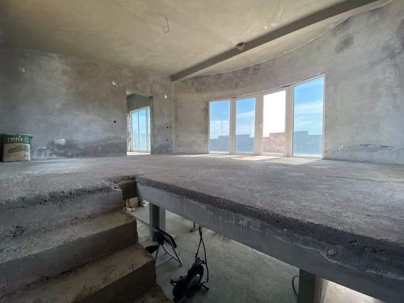Dnevna soba u kući pred završne radove u Šušnju, Crna Gora: betonski podovi, panoramski prozori i pogled na more.