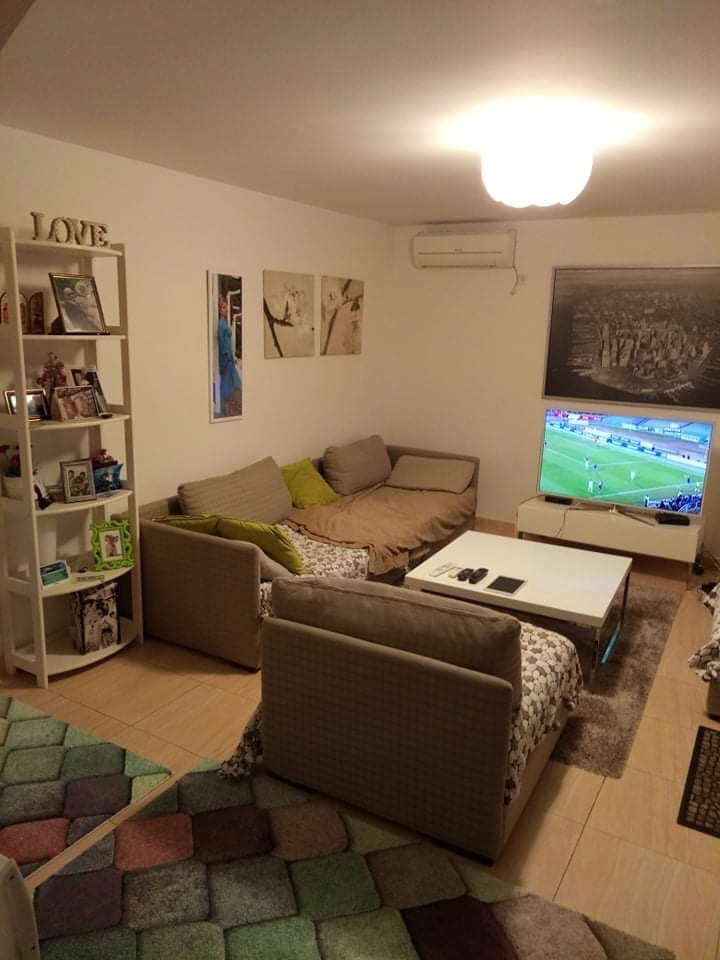 Ugodna dnevna soba sa sofom i TV-om u kući u Šušnju, Crna Gora: svetao enterijer, polica i klima-uređaj.