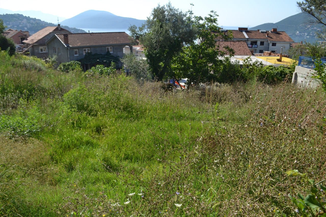 Baugrundstück in Herceg Novi, Montenegro, mit Panoramablick auf die Berge und das Meer inmitten von Grün.