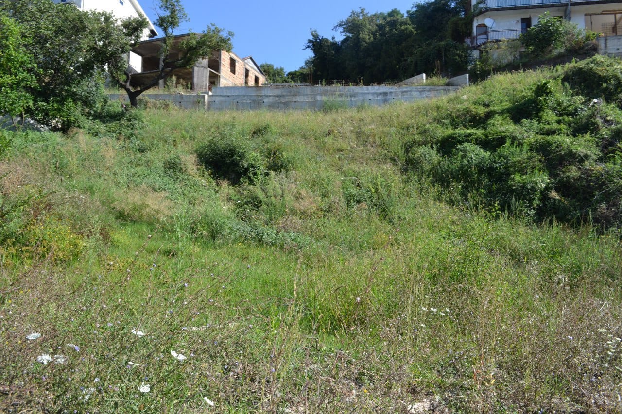 Baugrundstück in Herceg Novi, Montenegro: geneigtes Gelände mit Gras und Betonfundament.
