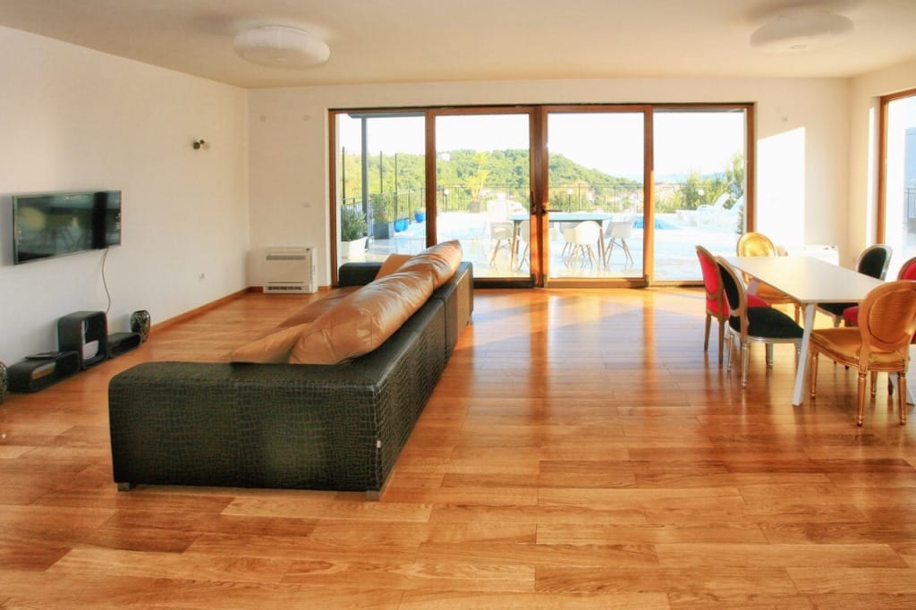 Spacious living room in a villa in Herceg Novi, Montenegro: leather sofa, dining area, and access to the pool on the terrace.