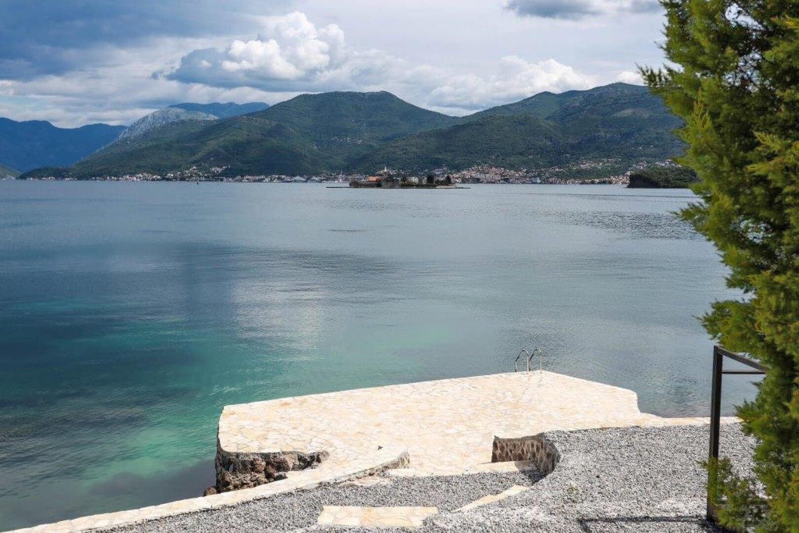 Вид на море и горы с частного каменного пляжа виллы в поселке Крашичи, Черногория, с выходом в воду по лестнице.