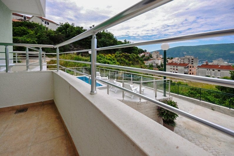 Balcon avec vue sur la mer et la piscine dans un appartement, Herceg Novi, Monténégro : garde-corps moderne et sol carrelé.