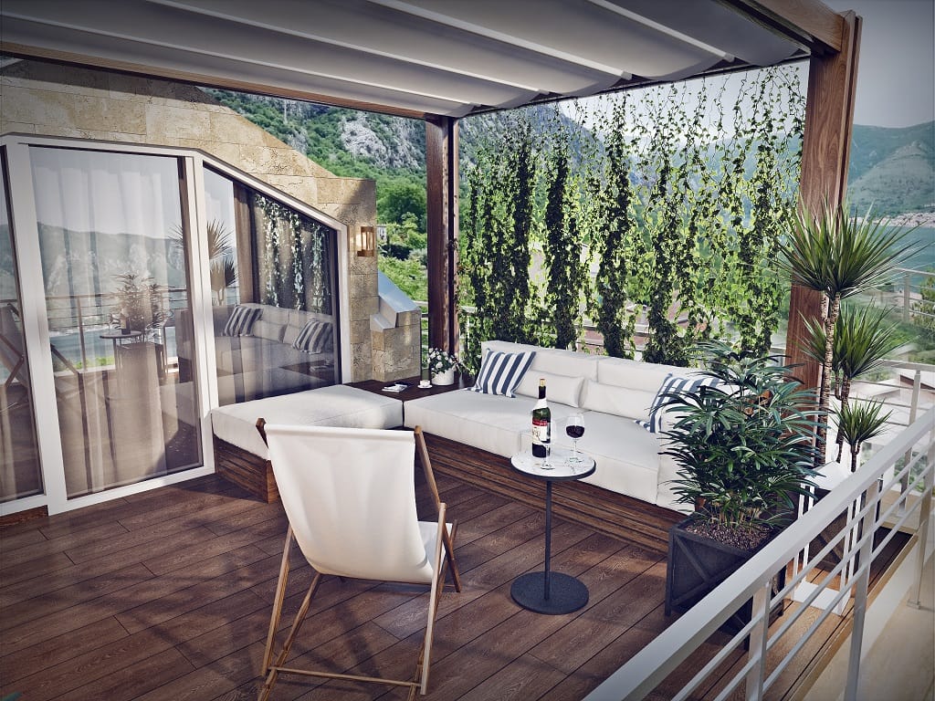 Gemütliche Terrasse mit Holzbelag und weichen Möbeln in einer Wohnung in Dobrota, Montenegro, mit Blick auf die Berge und das Meer.