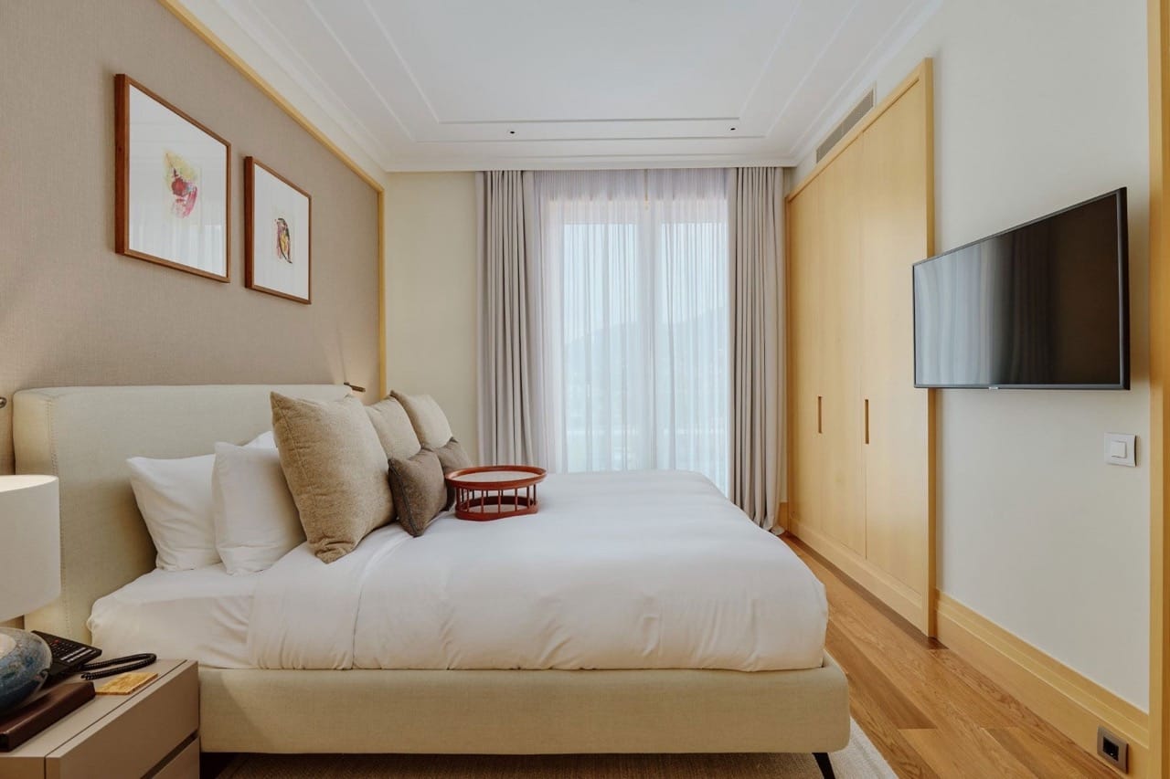 Savremena spavaća soba u stanu Porto Montenegro, Tivat, Crna Gora: bračni krevet, svetao nameštaj i TV.