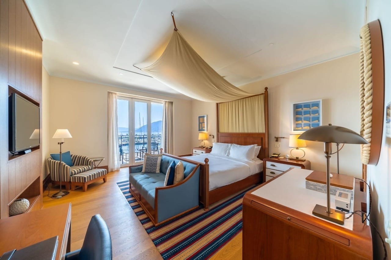 Spavaća soba u apartmanima Porto Montenegro, Tivat, Crna Gora: krevet s baldahinom, pogled na marinu i stilizovan enterijer.