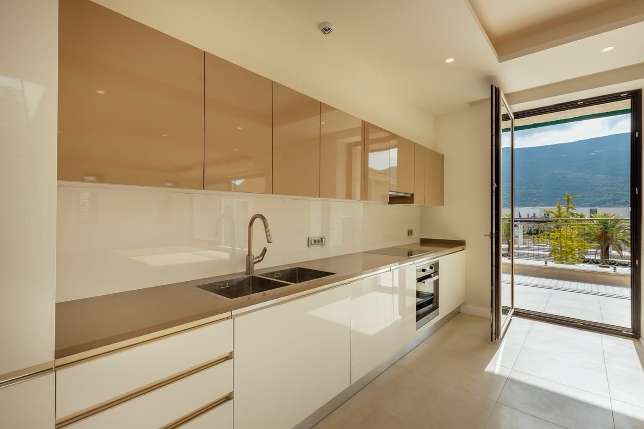 Modern kitchen in a villa in Portonovi, Kumbor, Montenegro: glossy cabinets, built-in appliances, and access to the terrace.