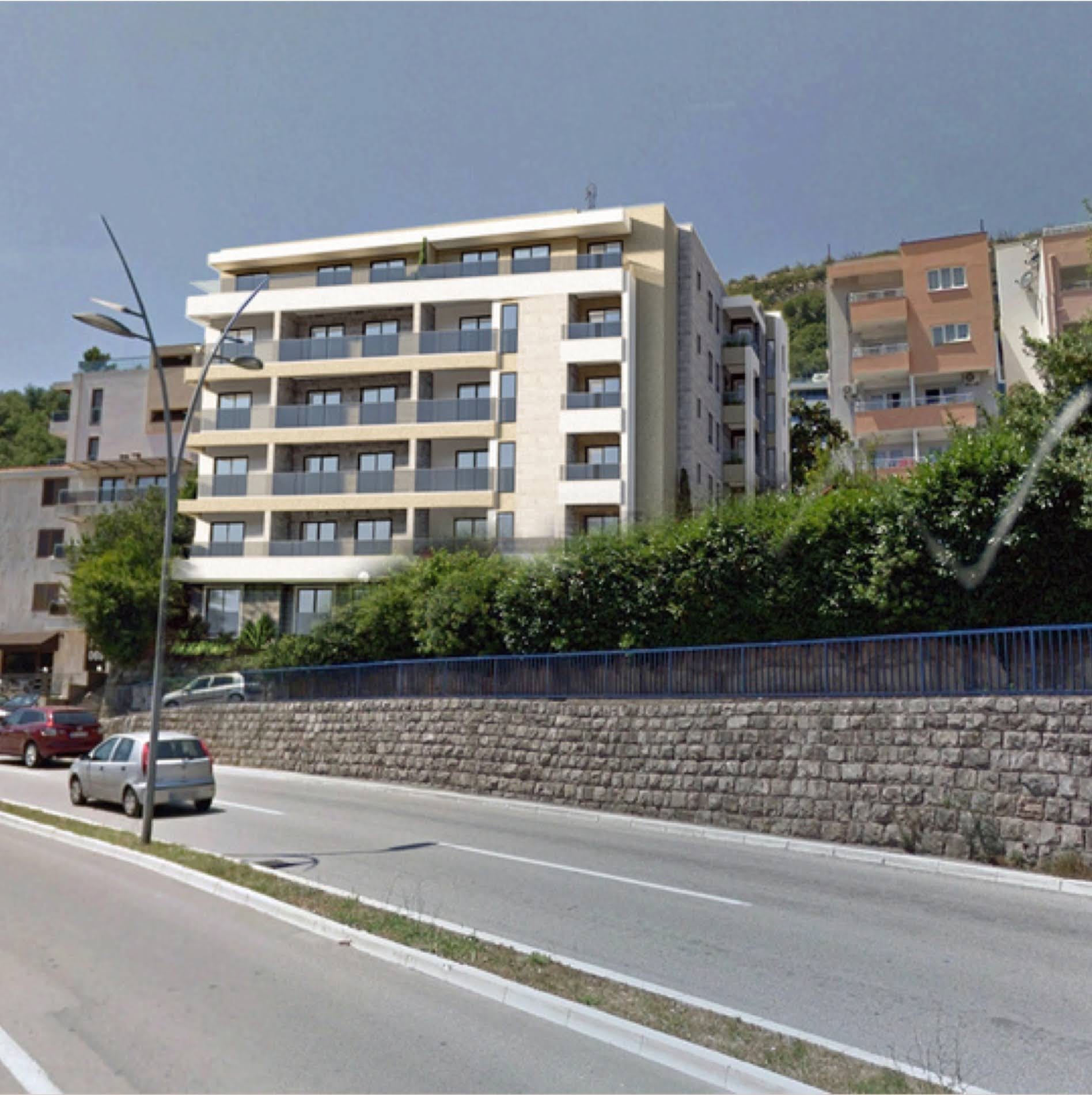 Modern residential complex with balconies and stone facade finish in Budva, Montenegro, road view.