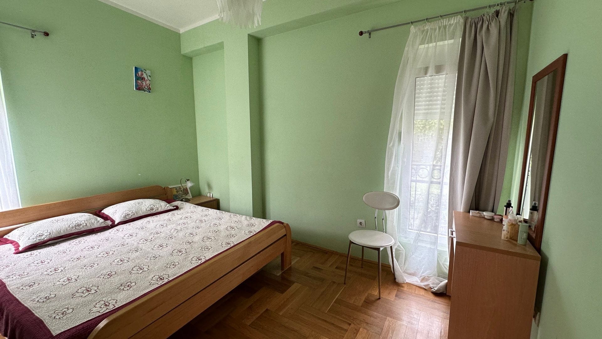 Светлая спальня с двуспальной кроватью и паркетом в квартире на продажу, Будва, Черногория.