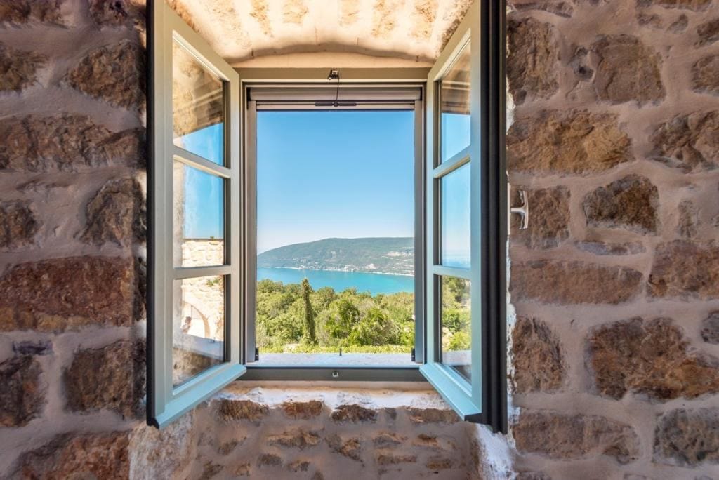 Sea and mountain view from the window of a stone villa in Herceg Novi, Montenegro: interior with authentic stone walls.