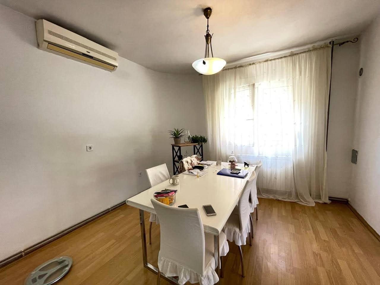 Bright living room with dining area in a house, Bar, Montenegro: white table, chairs, and air conditioner in the interior.