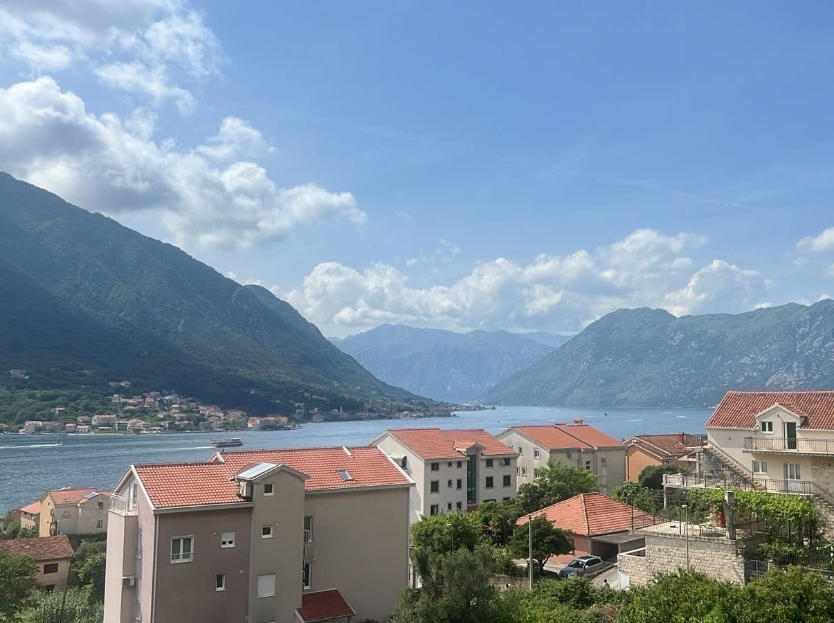 Panoramablick auf die Bucht von Kotor und die Berge von einem Apartment in Dobrota, Montenegro: Wohngebiet mit Häusern und Ziegeldächern.