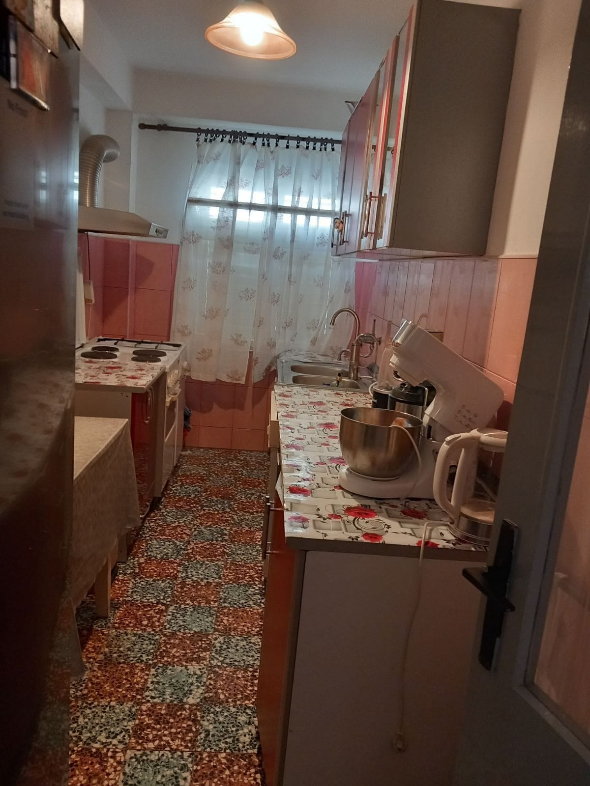 Уютная кухня в доме в Игало, Черногория: кухонный гарнитур, бытовая техника, плитка с узором и окно с занавесками.