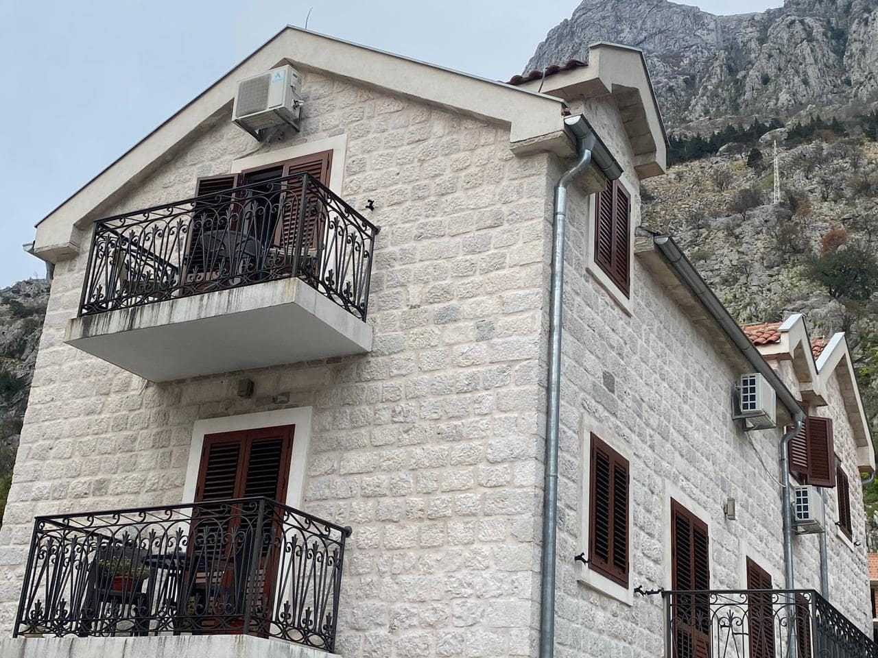 Facade of a stone house with wrought-iron balconies in Kotor, Montenegro: Mediterranean-style apartments at the foot of the mountains.