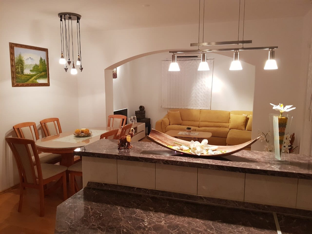 Şuşanj, Karadağ'daki bir evde yemek alanı içeren oturma odası iç mekanı: sarı kanepe, mermer bar tezgahı ve dekor.