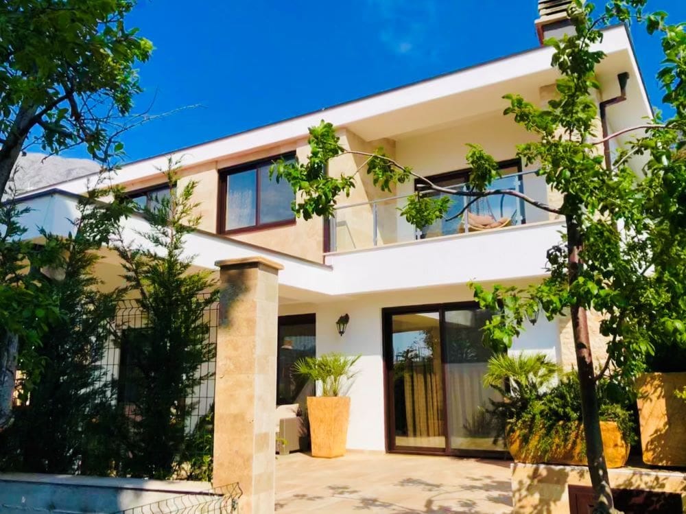 Dvospratna vila sa terasom i vrtom u Dobrim Vodama, Crna Gora: moderna fasada, panoramski prozori i zelena parcela.