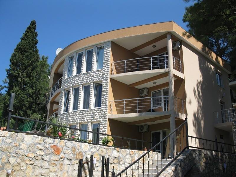 Villa de trois étages à Šušanj, Monténégro : façade moderne avec finitions en pierre, balcons et fenêtres panoramiques.