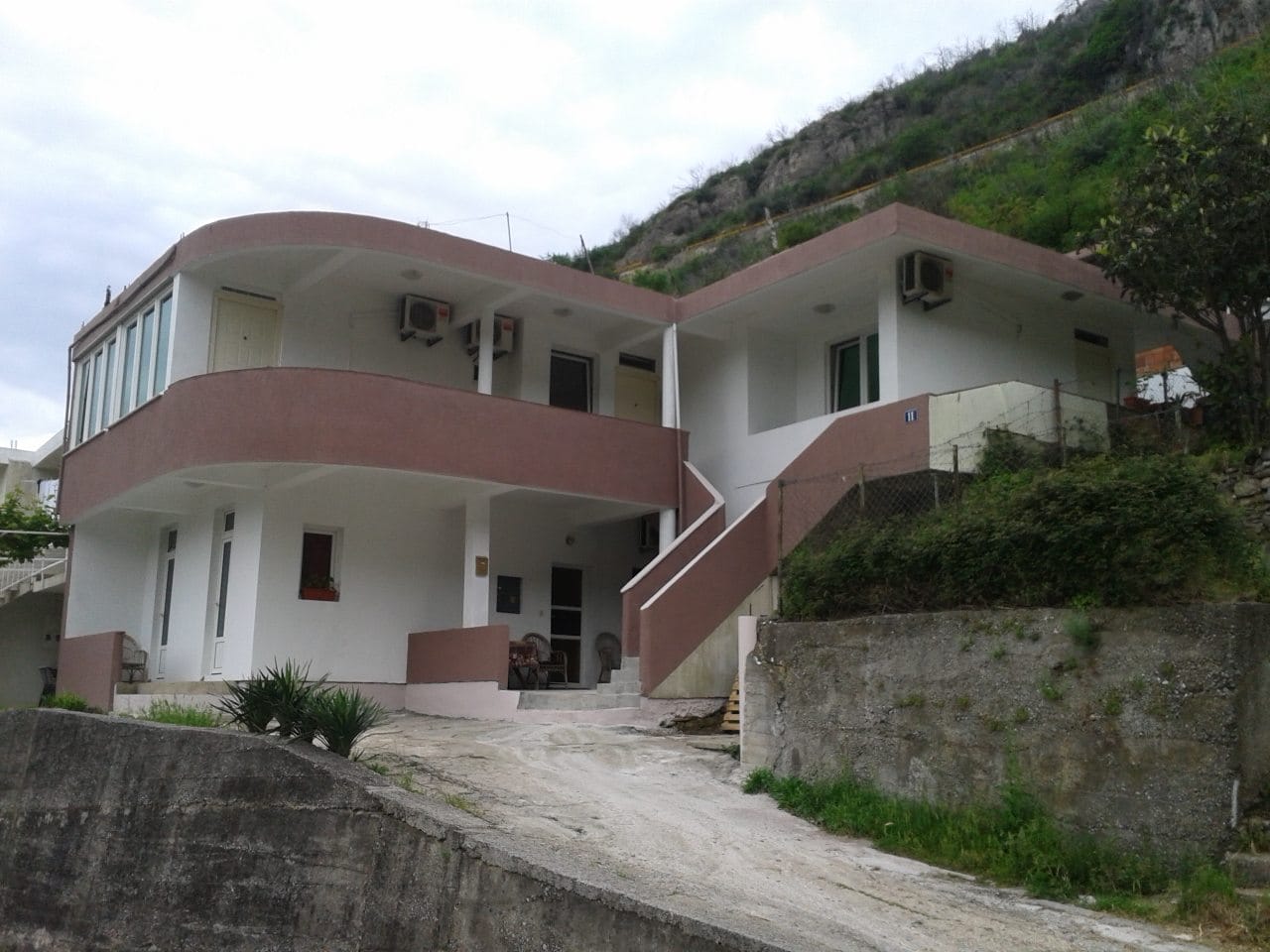 Dvospratna kuća u Budvi, Crna Gora: moderna fasada sa terasama, spoljašnje stepenište i pogled na planinski pejzaž.