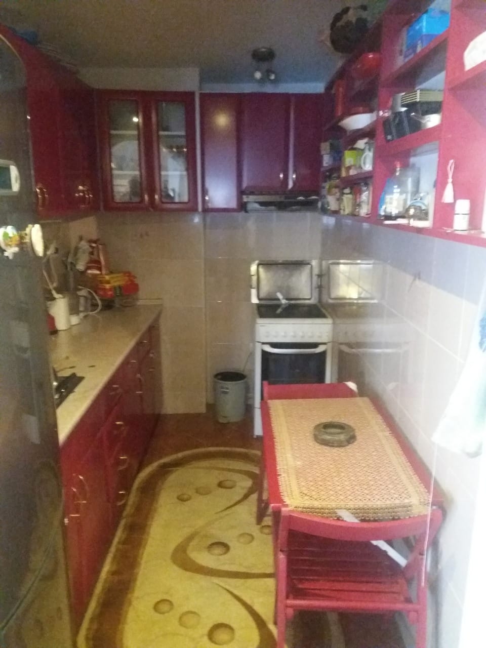 Кухня с красным гарнитуром, обеденным столом и плитой в доме на продажу в Муо, Черногория.