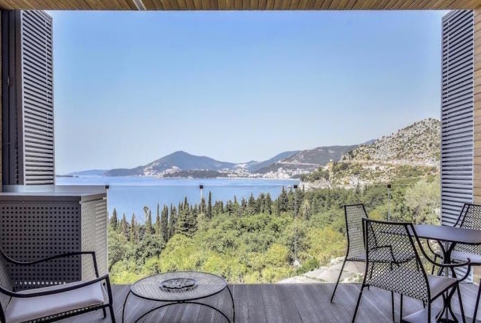Терраса квартиры в Каменово, Черногория: вид на море, горы и сад, современная мебель, деревянный настил пола.