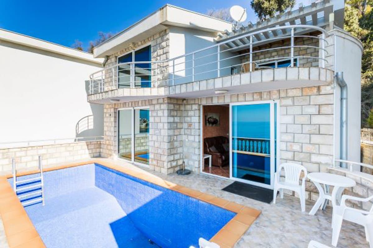 Maison à deux étages avec piscine et vue sur la mer dans le village de Kruče, Monténégro : façade en pierre et terrasse.