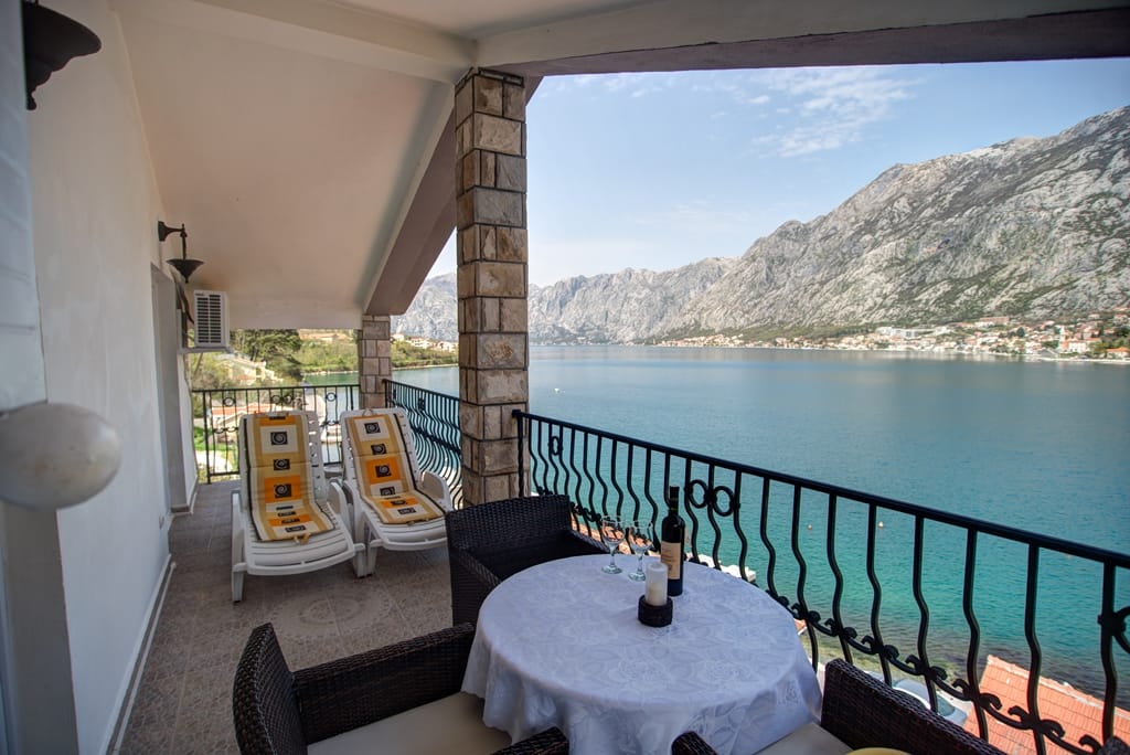 Terrace with a view of the Bay of Kotor, rattan furniture, and sun loungers at a house in Muo, Montenegro.