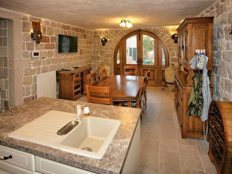 Interieur einer Wohnküche mit Steinwänden und Holzmöbeln in einer Villa in Reževići, Montenegro.