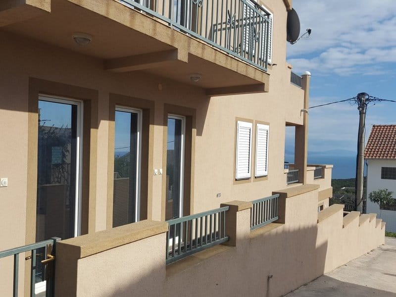 Fasada kuće u Krimovici, Crna Gora: terasa sa ogradom, panoramski prozori i pogled na more tokom sunčanog dana.