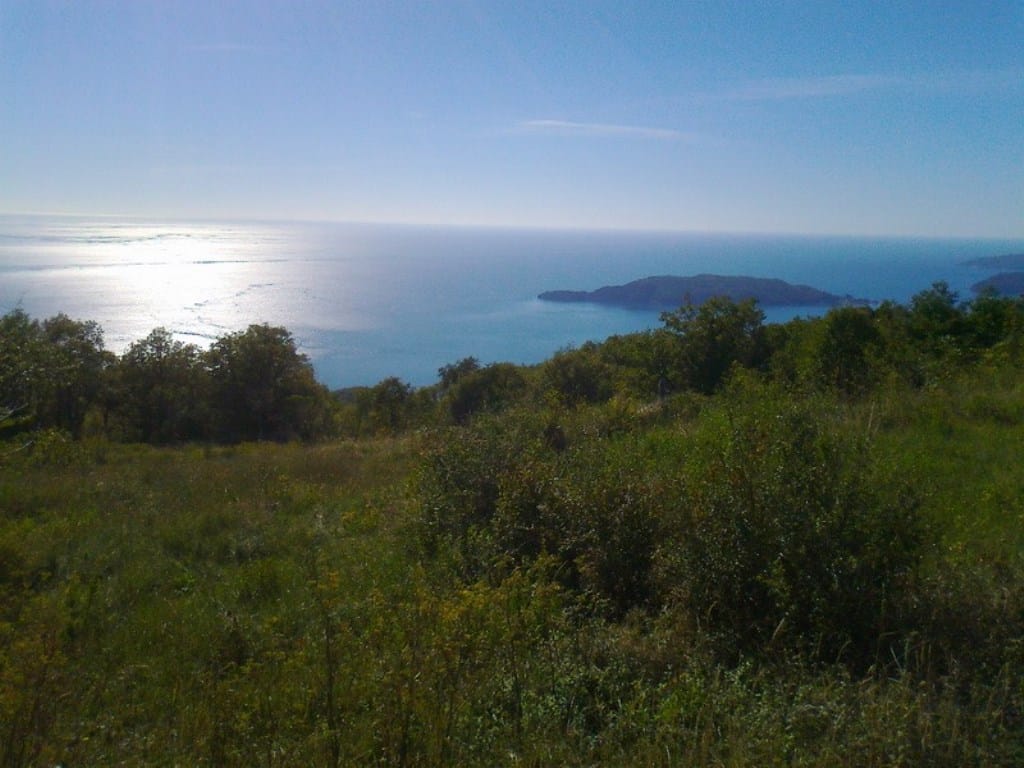 Panoramic sea and island view from a land plot in Kuljače, Montenegro: green hills and an open sea horizon.