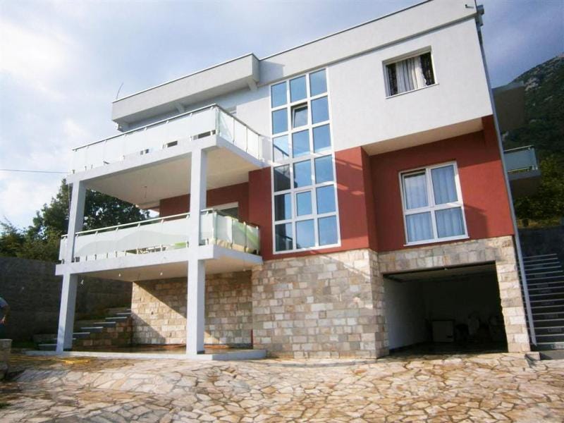 Nowoczesna willa w Sutomore, Czarnogóra: fasada z panoramicznymi oknami, tarasami i kamiennym wykończeniem cokołu.