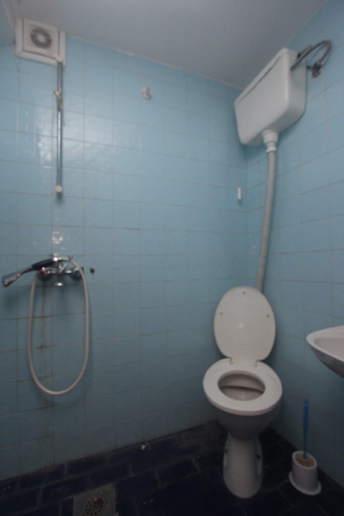Ванная комната с голубой плиткой и душем в доме на продажу в Муо, Черногория. Компактный санузел с сантехникой.