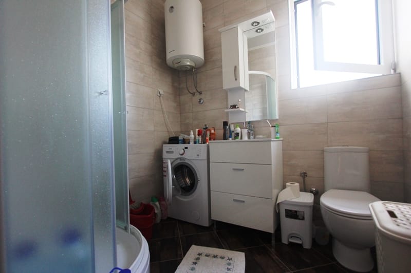 Bathroom in a house in Baošići, Montenegro: shower cabin, washing machine, vanity with mirror, and water heater.
