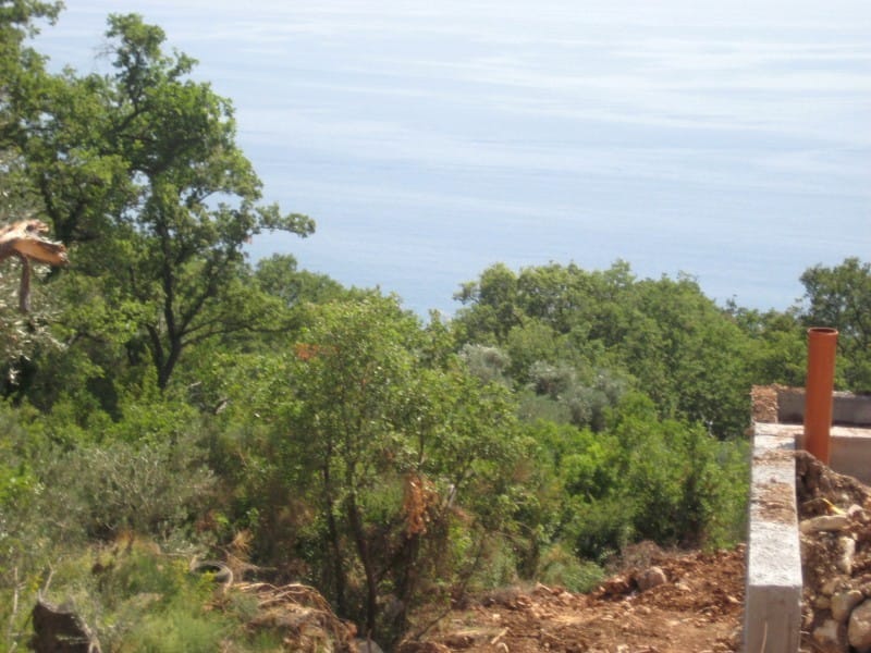 Вид на море с земельного участка под строительство в Режевичи, Черногория: панорама побережья и зеленый сад.