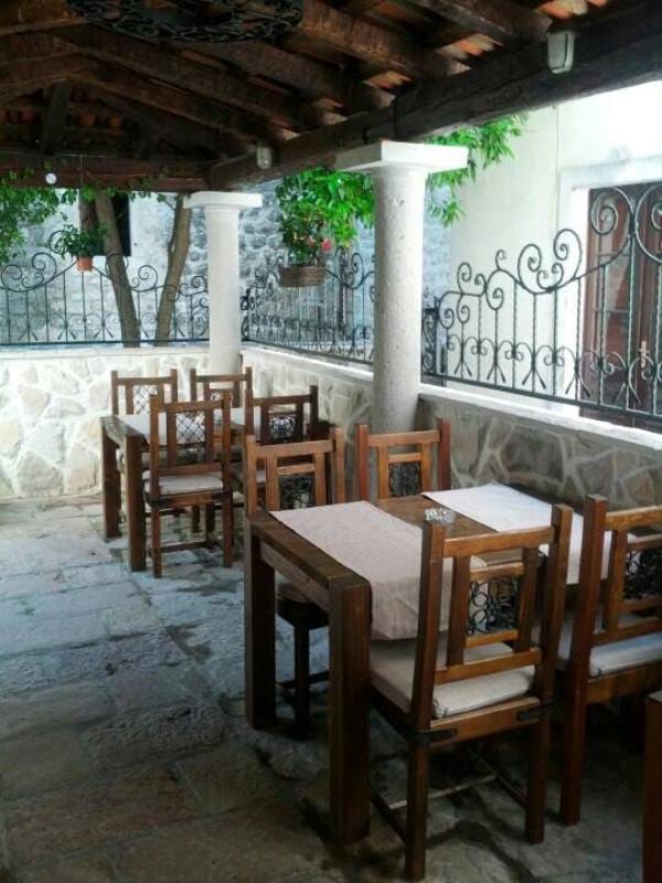 Covered terrace with wooden furniture in a stone house in Risan, Montenegro: a cozy lounge area with wrought-iron railings.