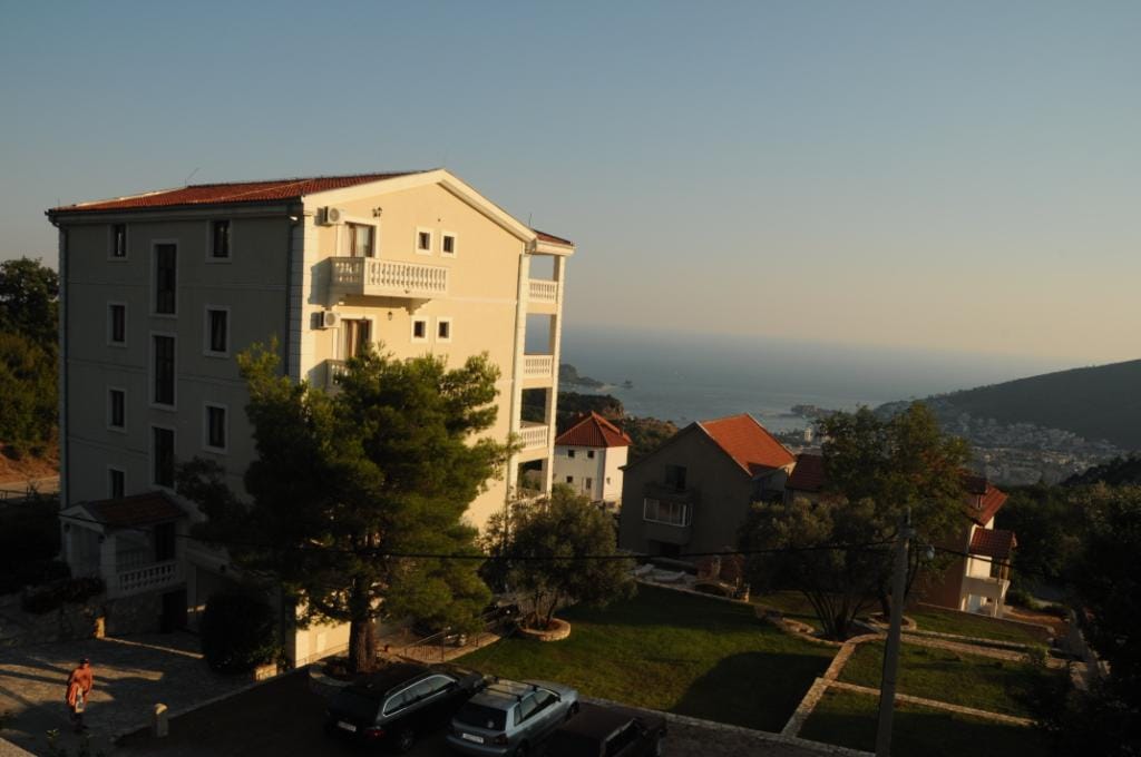 View of a residential villa in Markovichi, Montenegro, with parking, a green garden, and panoramic views of the Adriatic Sea.