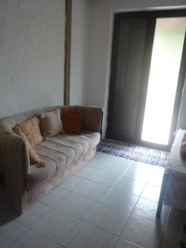 Living room with a sofa and tiled floor in a villa in Bigovo, Montenegro. Cozy interior with access to the terrace.
