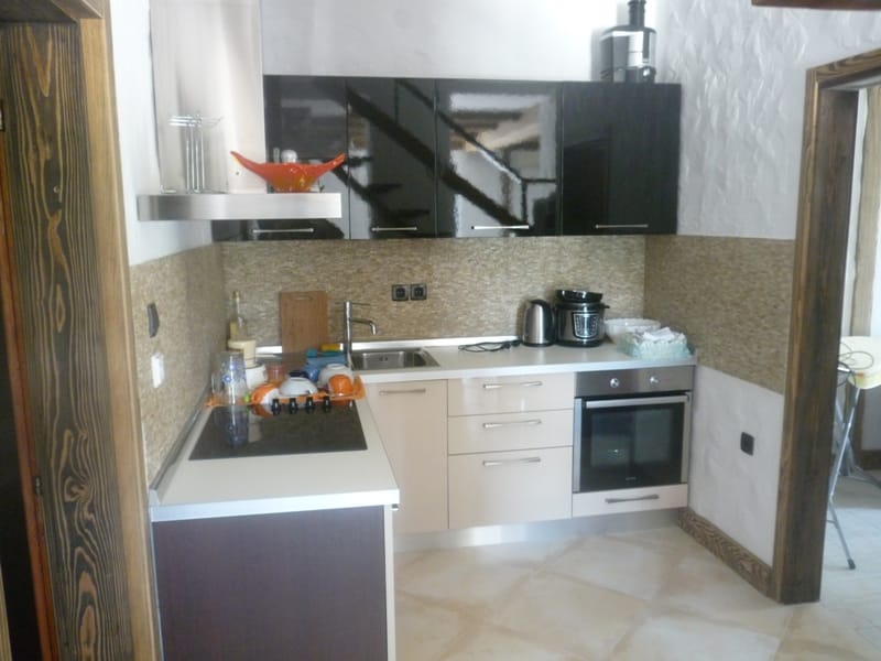 Modern kitchen in a villa in Bigovo, Montenegro: glossy fronts, built-in appliances, and a stone backsplash.