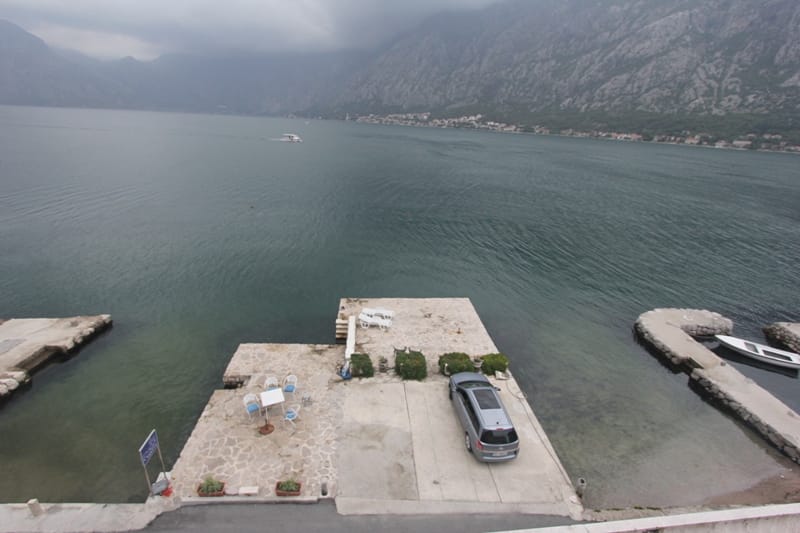 Вид на частный причал с зоной отдыха и парковкой у моря, вилла в Прчани, Которский залив, Черногория.