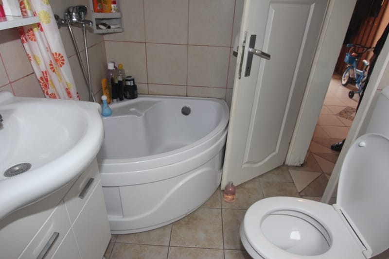 Ванная комната с угловой ванной и светлой плиткой в доме на продажу в Муо, Черногория.