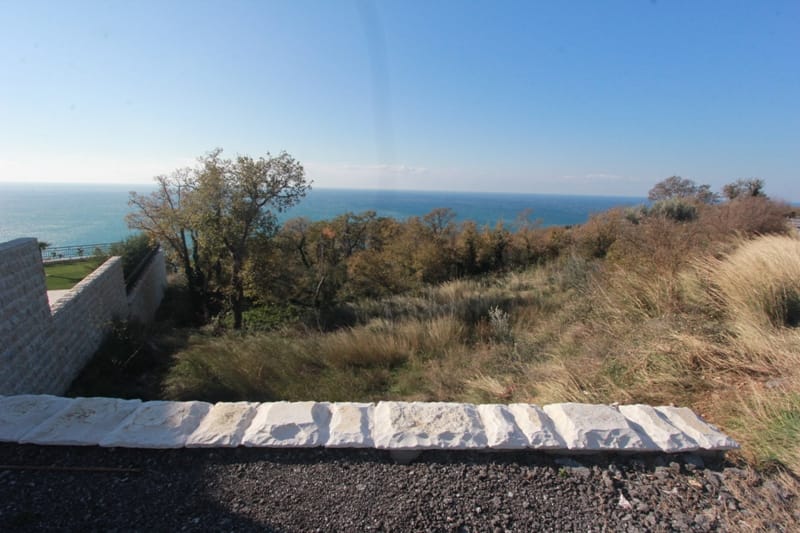 Grundstück in Reževići, Montenegro, mit Panoramablick auf die Adria und einer Steinmauer auf dem Gelände.