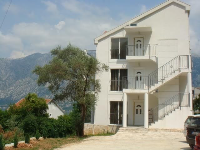 Dreistöckiges Haus mit Apartments in Stoliv, Montenegro: Fassadenansicht mit Außentreppen und Bergpanorama.