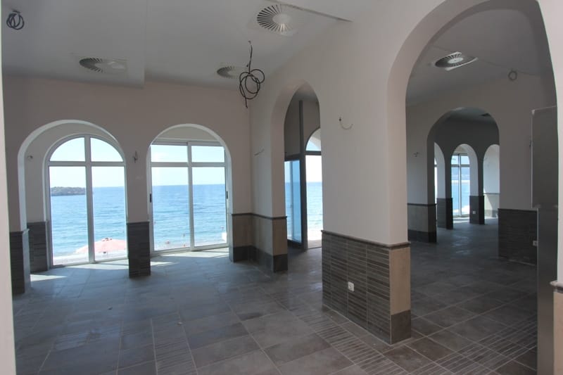 Restaurant space in Sveti Stefan, Montenegro: arched windows, sea view, tiled floor, and tiled wall finish.