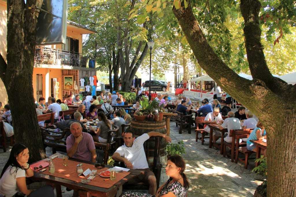 Summer terrace of a restaurant in Virpazar, Montenegro: wooden tables, shady trees, and a cozy atmosphere for relaxation.
