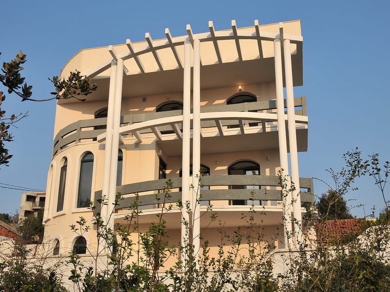 Maison de trois étages à Utjeha, Monténégro : façade moderne avec colonnes, fenêtres en arc et terrasses spacieuses.